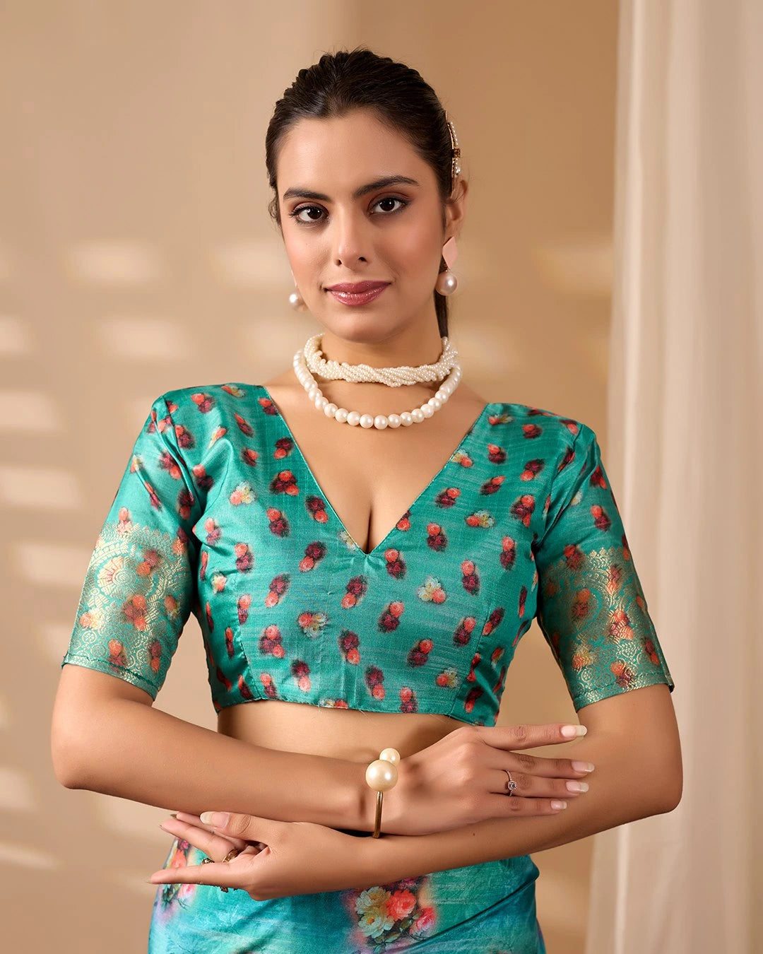 Woman wearing a turquoise blouse with floral patterns against a beige background