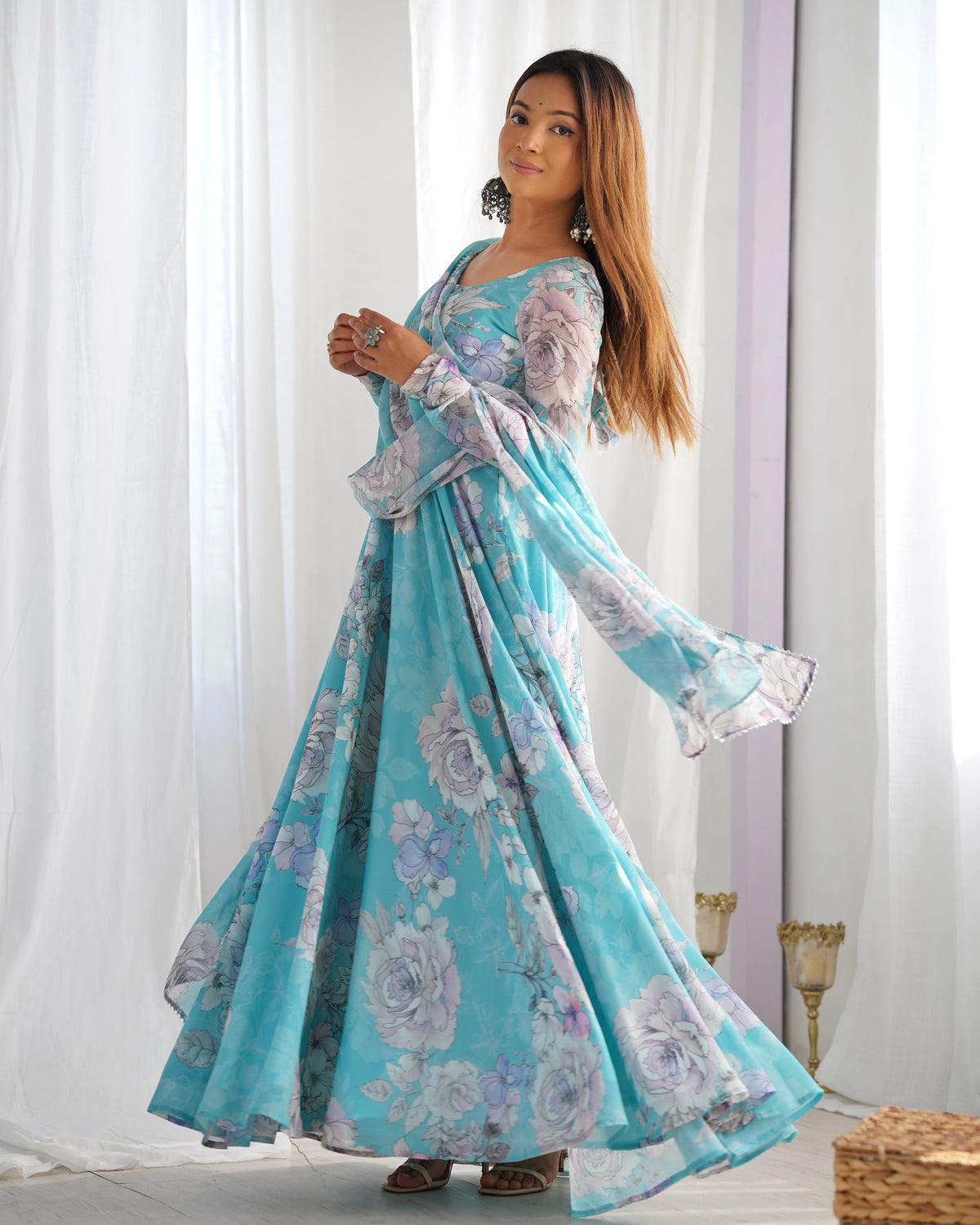 Woman wearing a floral dress standing in front of white curtains