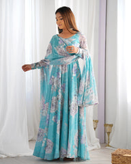 Woman wearing a blue floral dress standing in front of white curtains