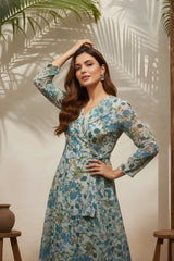 Woman wearing a floral dress standing against a wall with leaf shadows