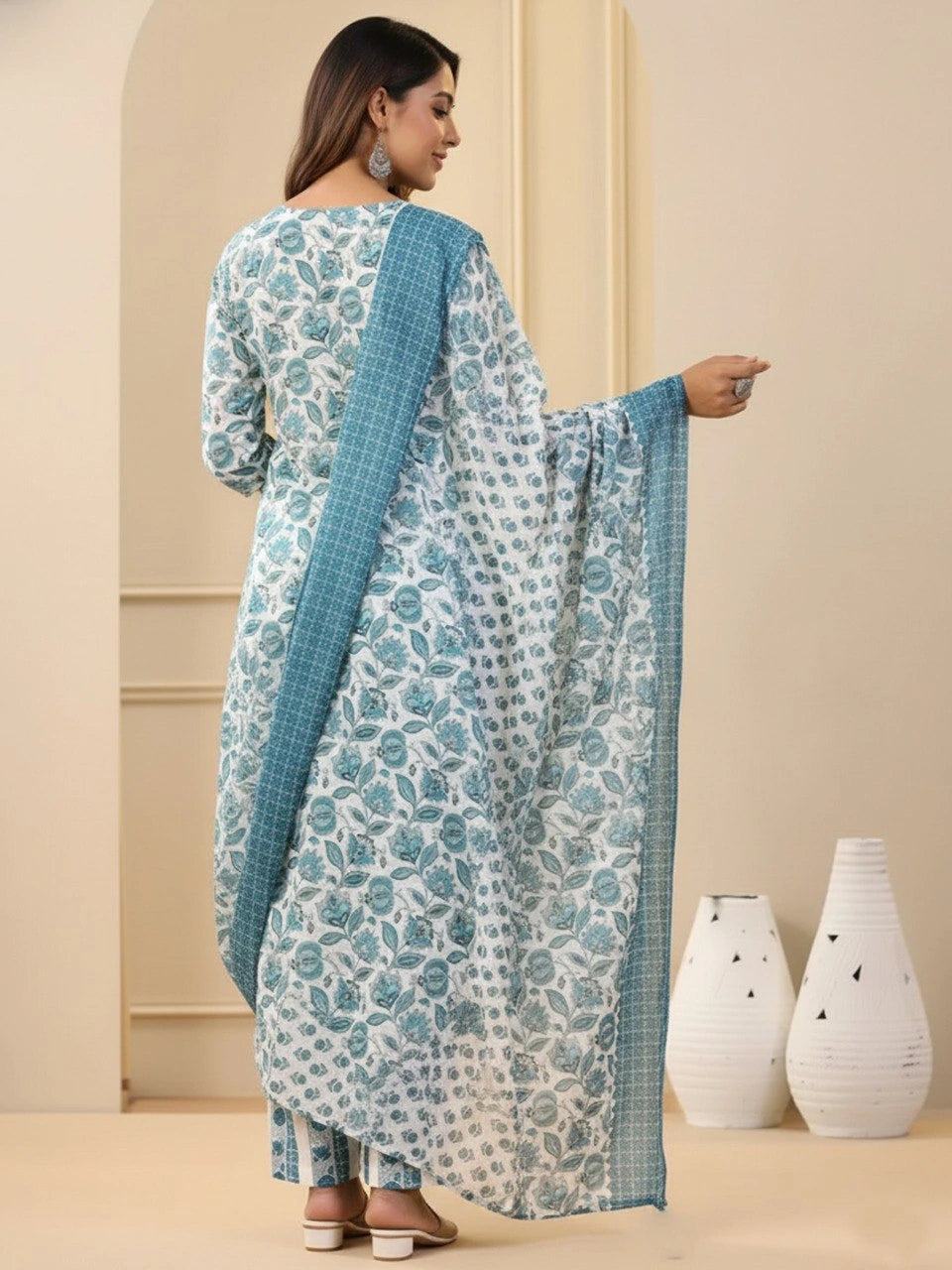 Woman wearing a floral dress with a blue dupatta in an indoor setting.