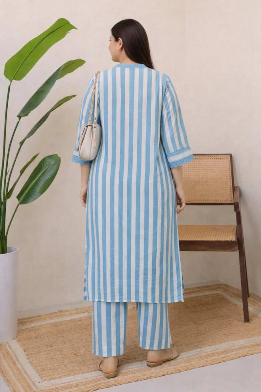 Woman wearing a blue and white striped outfit standing in a room with a plant and chair.