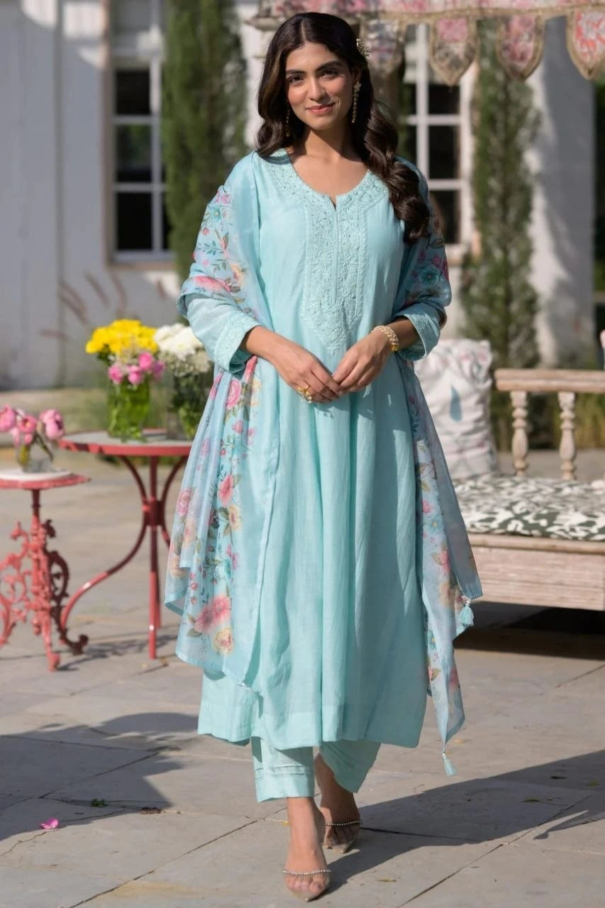 Woman in a light blue traditional outfit standing outdoors with decorative elements.
