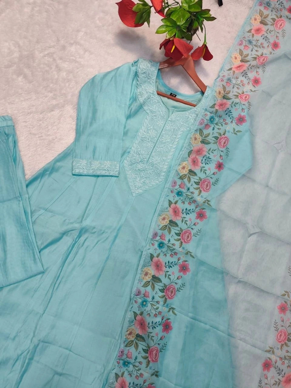 Light blue traditional outfit with floral embroidery on a light gray background