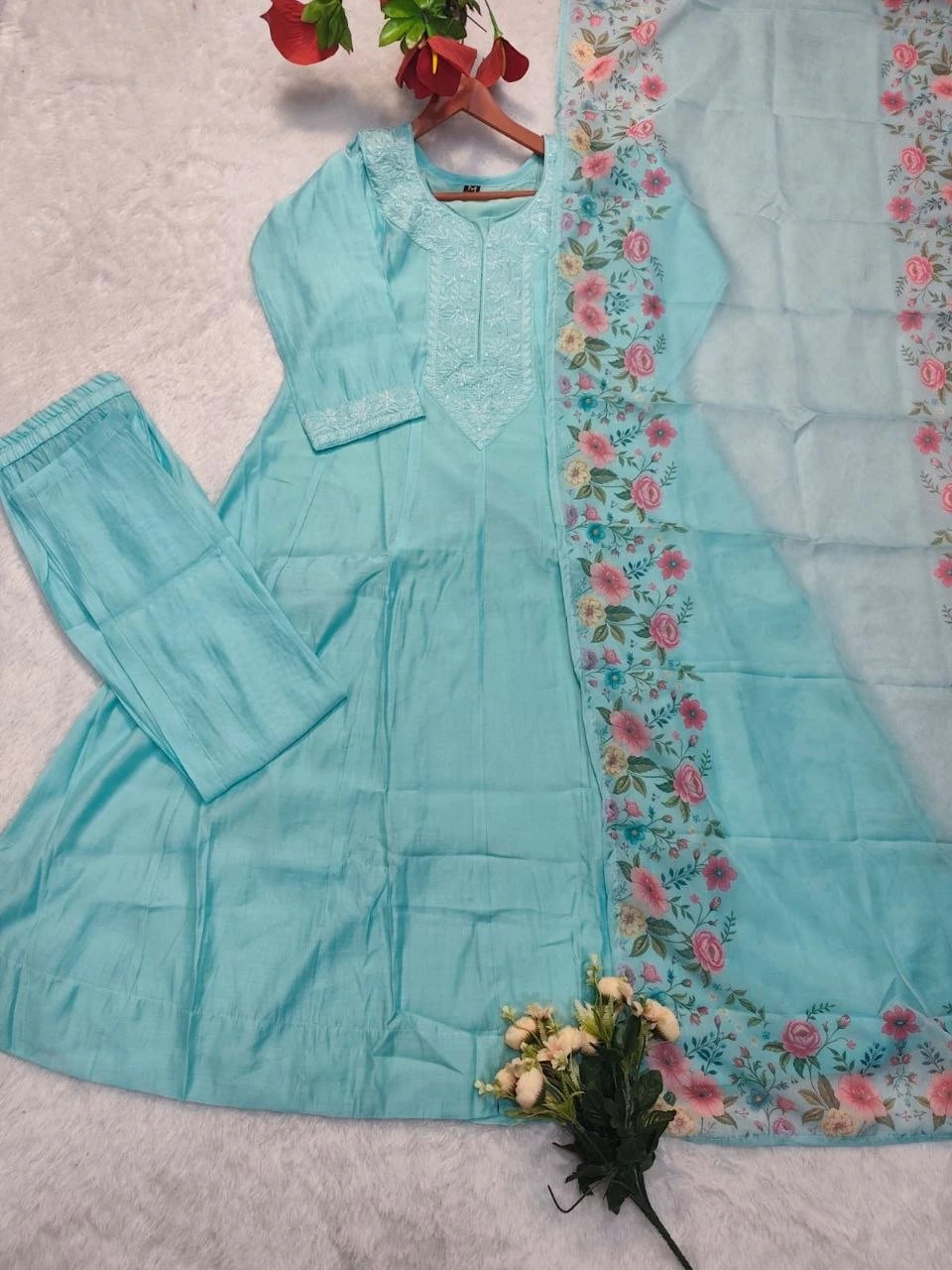 Light blue traditional outfit with floral embroidery on a textured surface