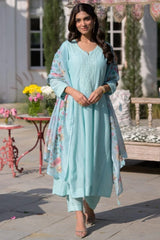 Woman in a light blue traditional outfit standing outdoors with decorative elements.