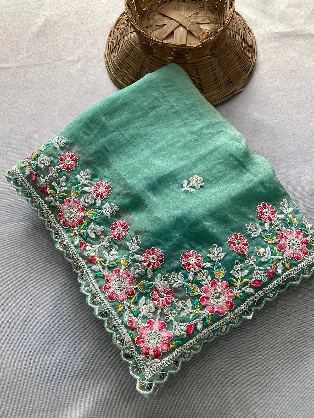 Green embroidered fabric with floral patterns on a light gray background
