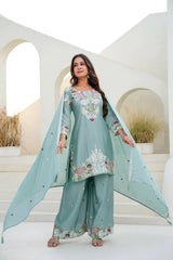 Woman wearing a light blue embroidered traditional outfit in an outdoor setting.