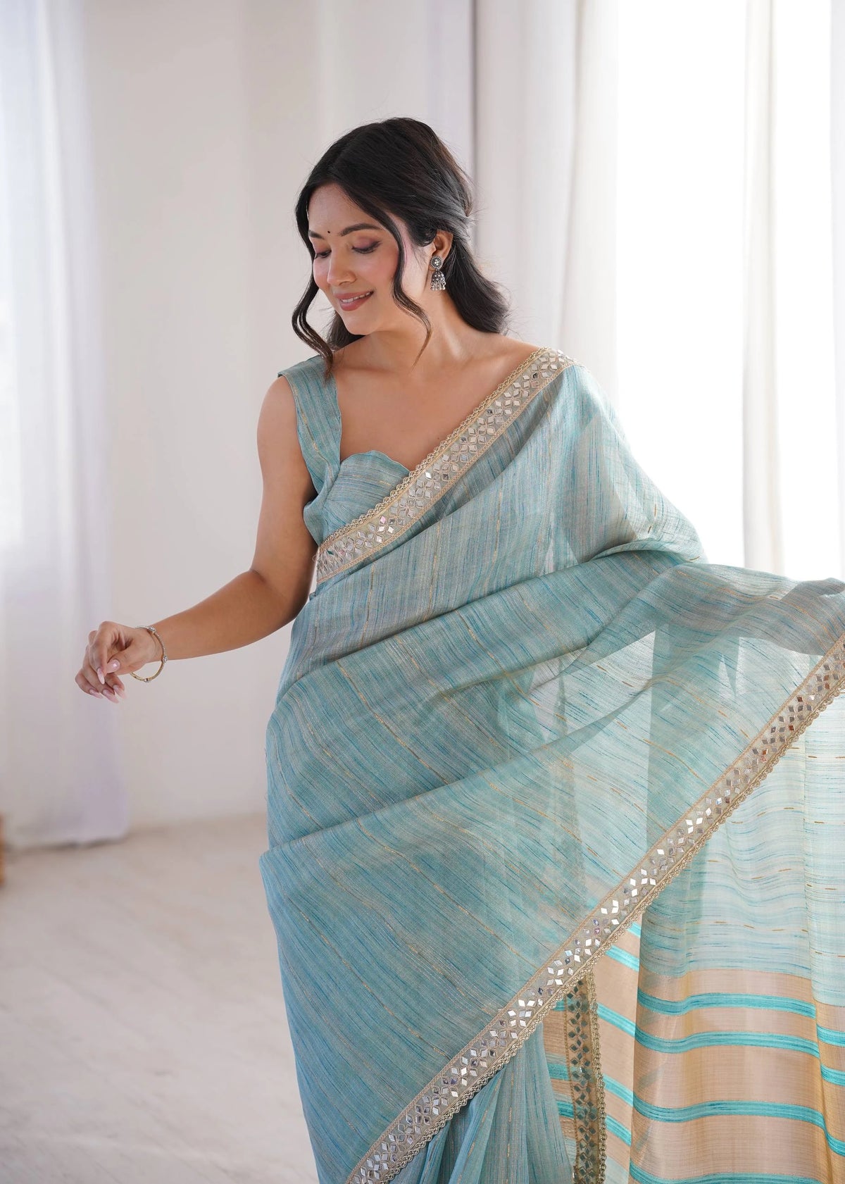 Woman wearing a light blue saree with a white background