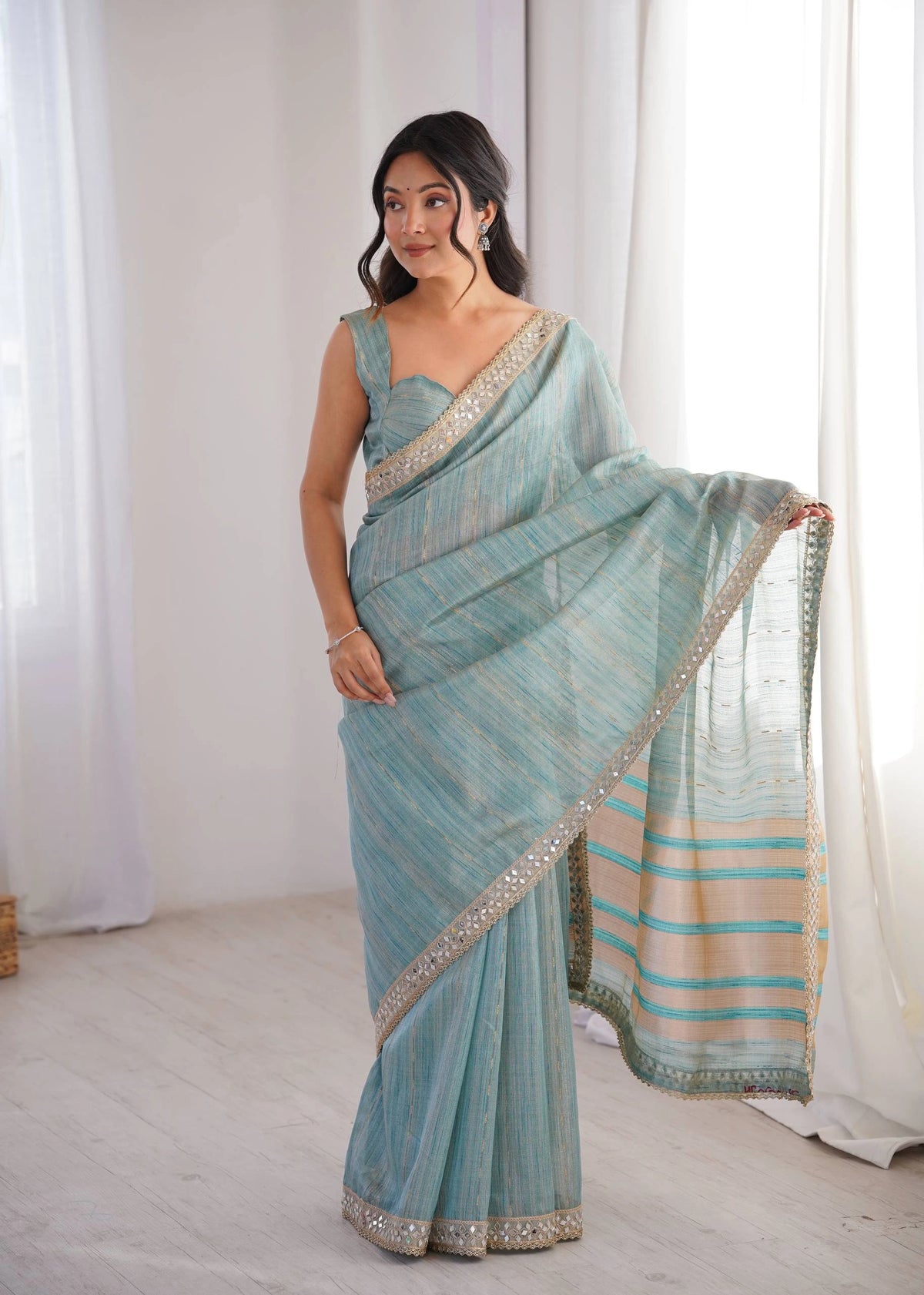 Woman wearing a light blue saree with a white background