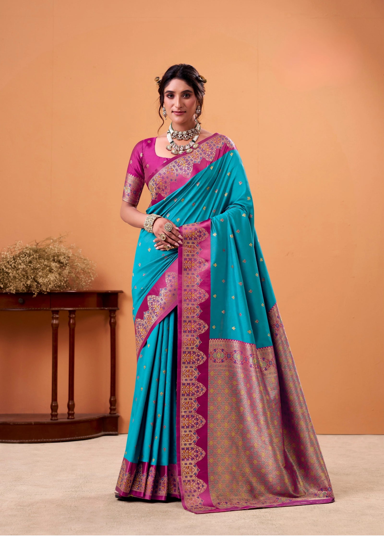 Woman wearing a blue and pink saree with a matching blouse against an orange background