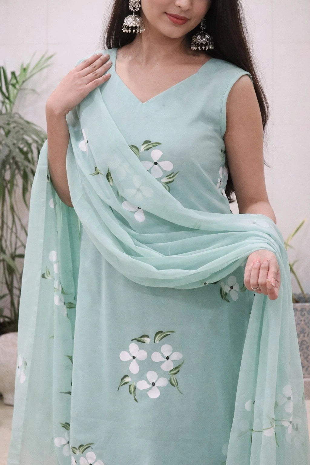 Woman wearing a light blue saree with floral patterns against a neutral background