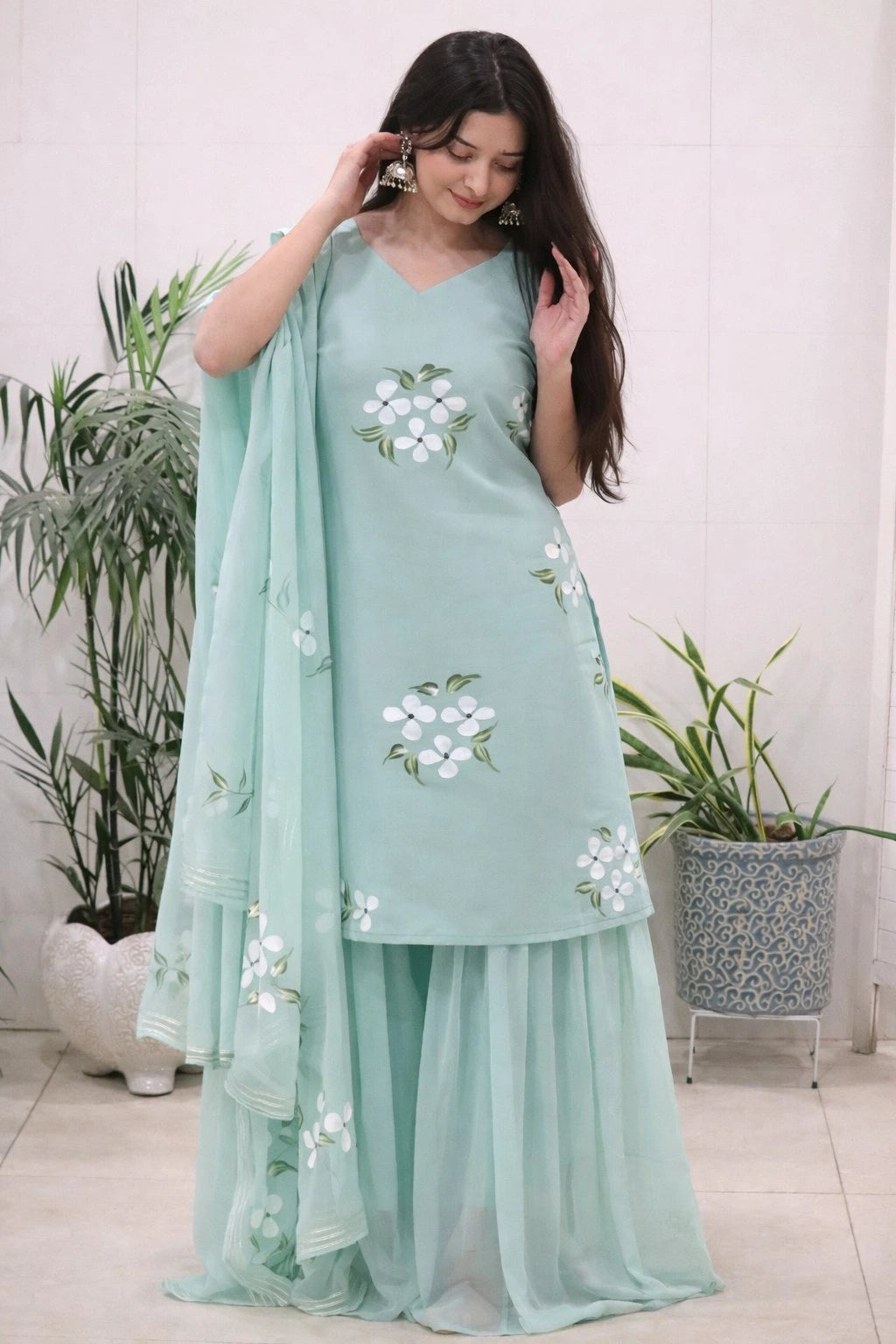 Woman wearing a light blue traditional outfit with floral patterns indoors.
