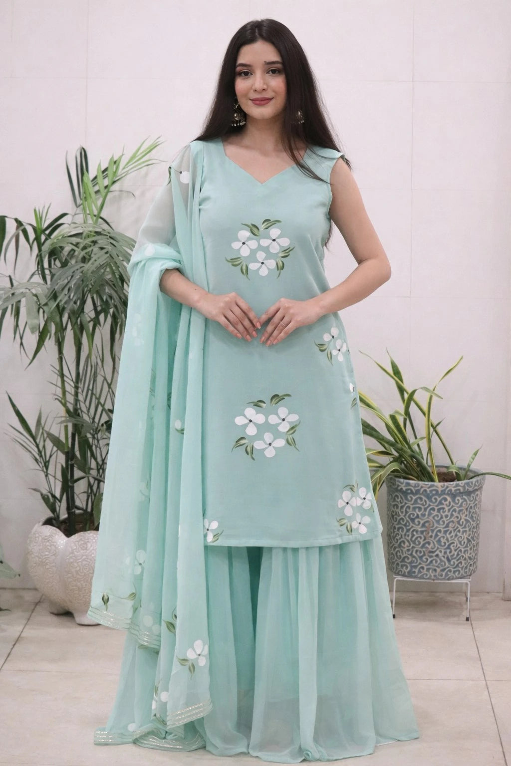 Woman wearing a light blue traditional outfit with floral patterns in a home setting.