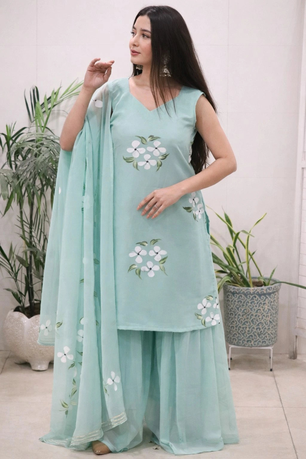 Woman wearing a light blue traditional outfit with floral patterns indoors.
