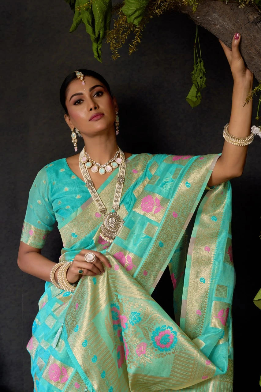 Woman in a traditional turquoise and pink saree with jewelry against a dark background