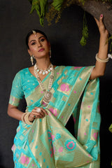 Woman in a traditional turquoise and pink saree with jewelry against a dark background