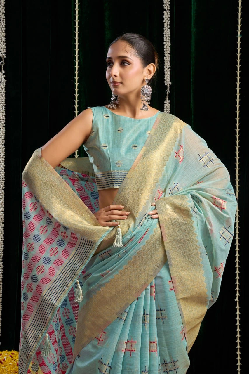 Woman wearing a light blue saree with a patterned border against a dark background