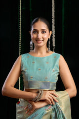 Woman wearing a traditional outfit with a green blouse and saree against a dark background