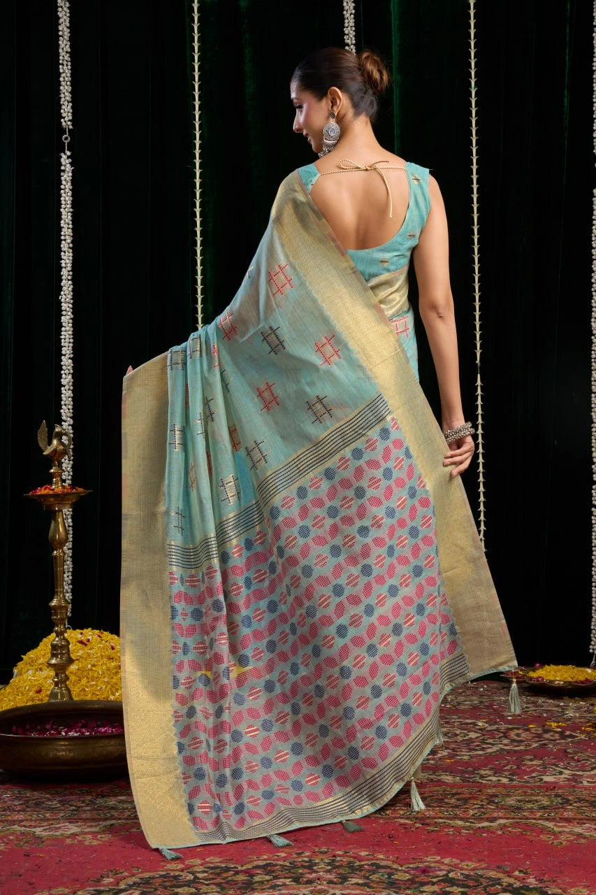 Woman in a traditional saree standing on a patterned floor with a dark background