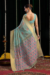 Woman in a traditional saree standing on a patterned floor with a dark background
