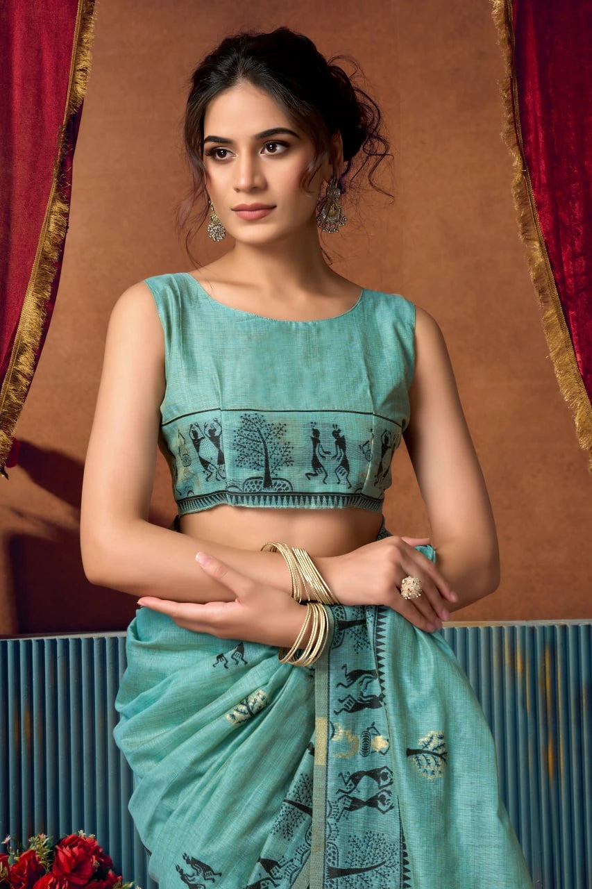 Woman wearing a traditional turquoise saree with intricate patterns against a decorative background