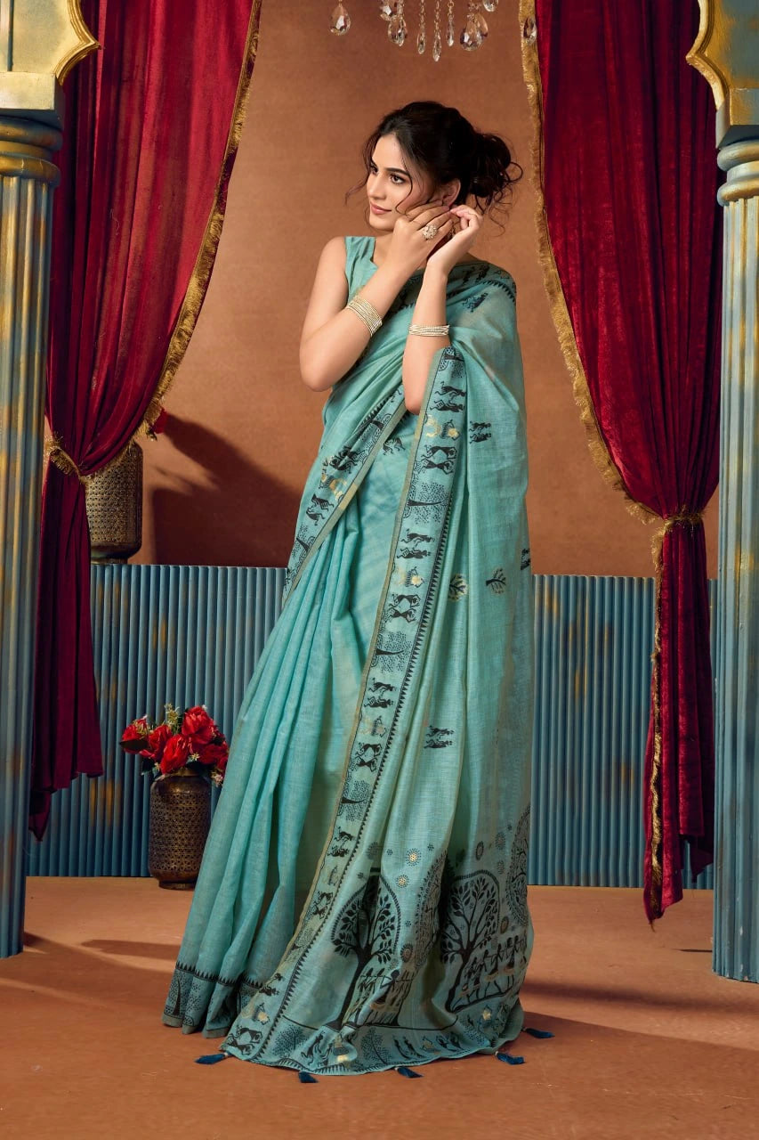 Woman in a light blue saree with a decorative border against a red curtain backdrop