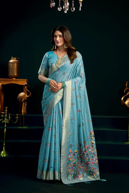 Woman wearing a light blue saree with a dark background