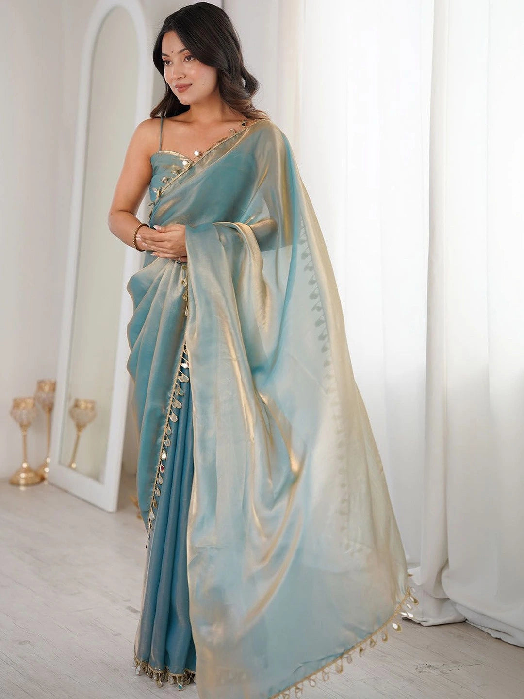 Woman wearing a light blue saree with a white background
