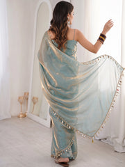 A rear view of the sky-blue blouse showing its minimalist sleeveless design with thin spaghetti straps and a straight-cut back. The saree is draped over one shoulder, revealing the clean lines of the blouse.