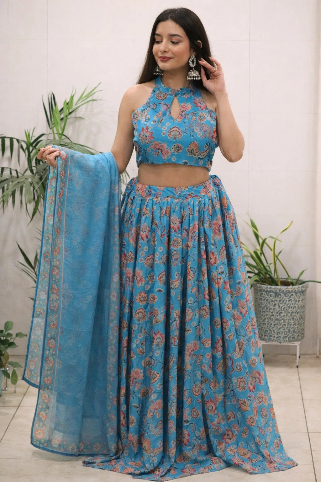 Woman wearing a blue floral outfit with a matching dupatta, standing indoors.