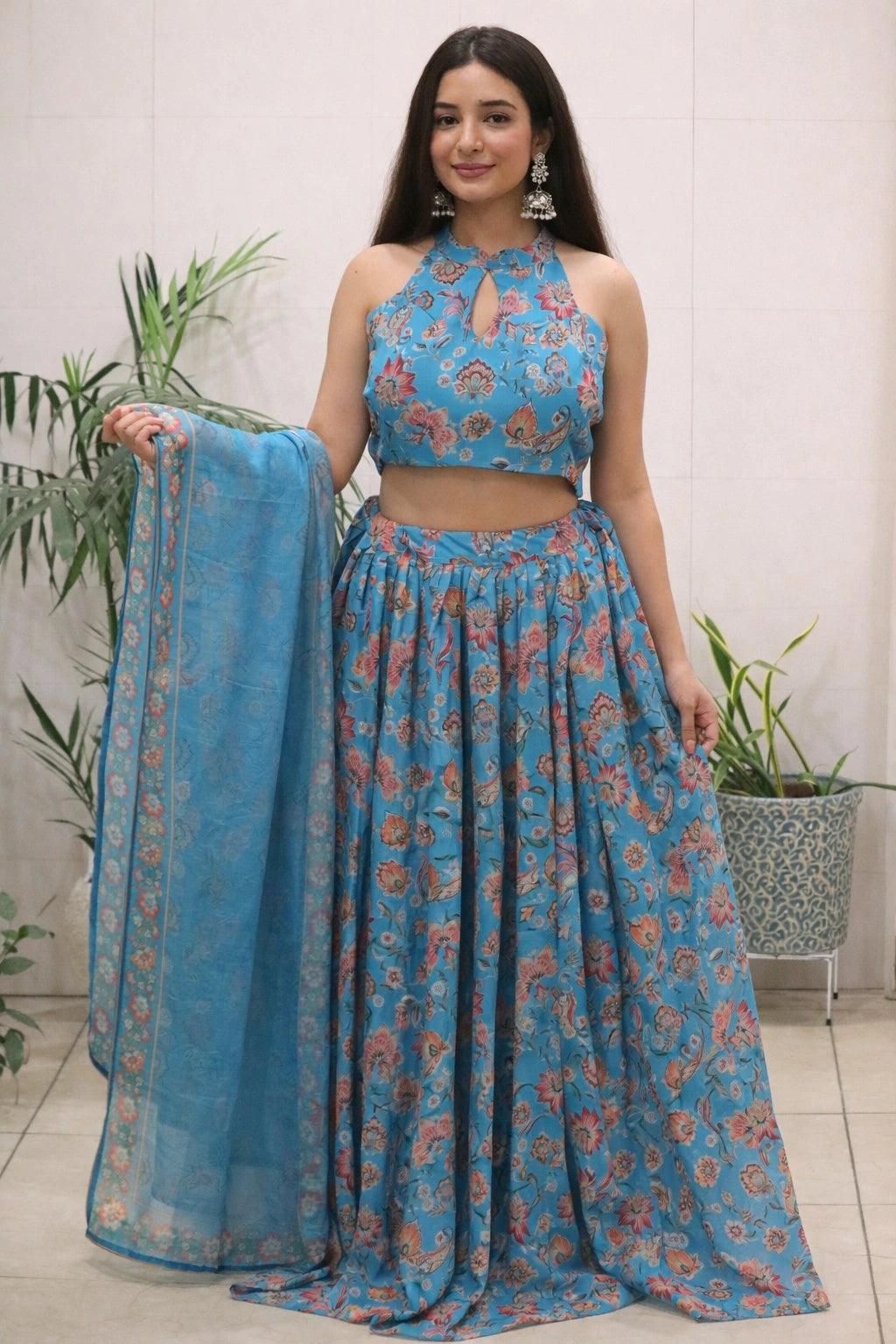 Woman wearing a blue floral outfit with a matching dupatta, standing indoors.