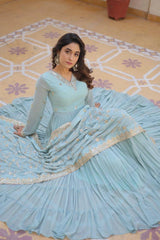 Woman in a light blue traditional outfit sitting on a patterned floor.