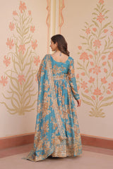 Woman in a floral dress standing against a decorative wall with floral patterns.