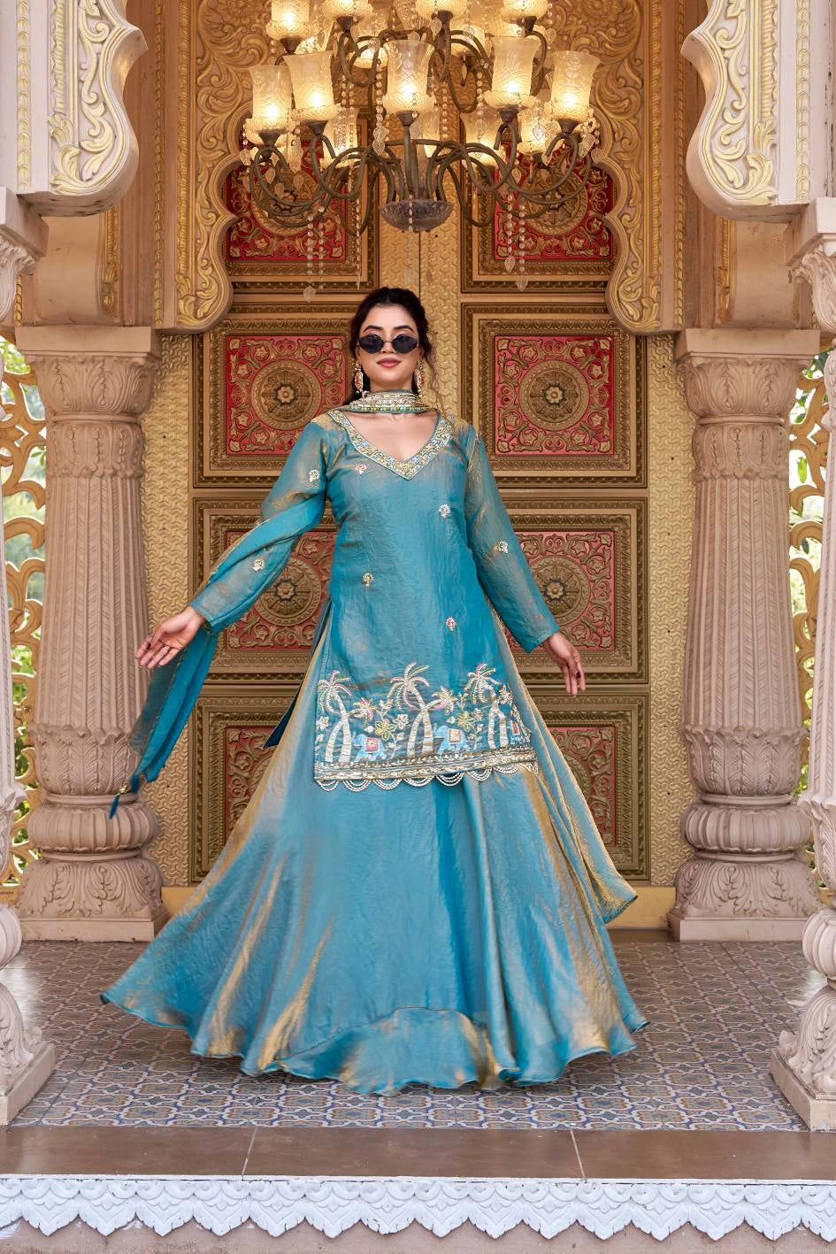 She wears an embroidered kurta paired with a flowing Sharara-style skirt and matching dupatta.
