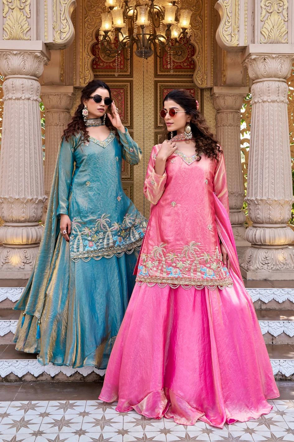 The flowing dupatta drapes elegantly along her side, enhancing the regal look.
