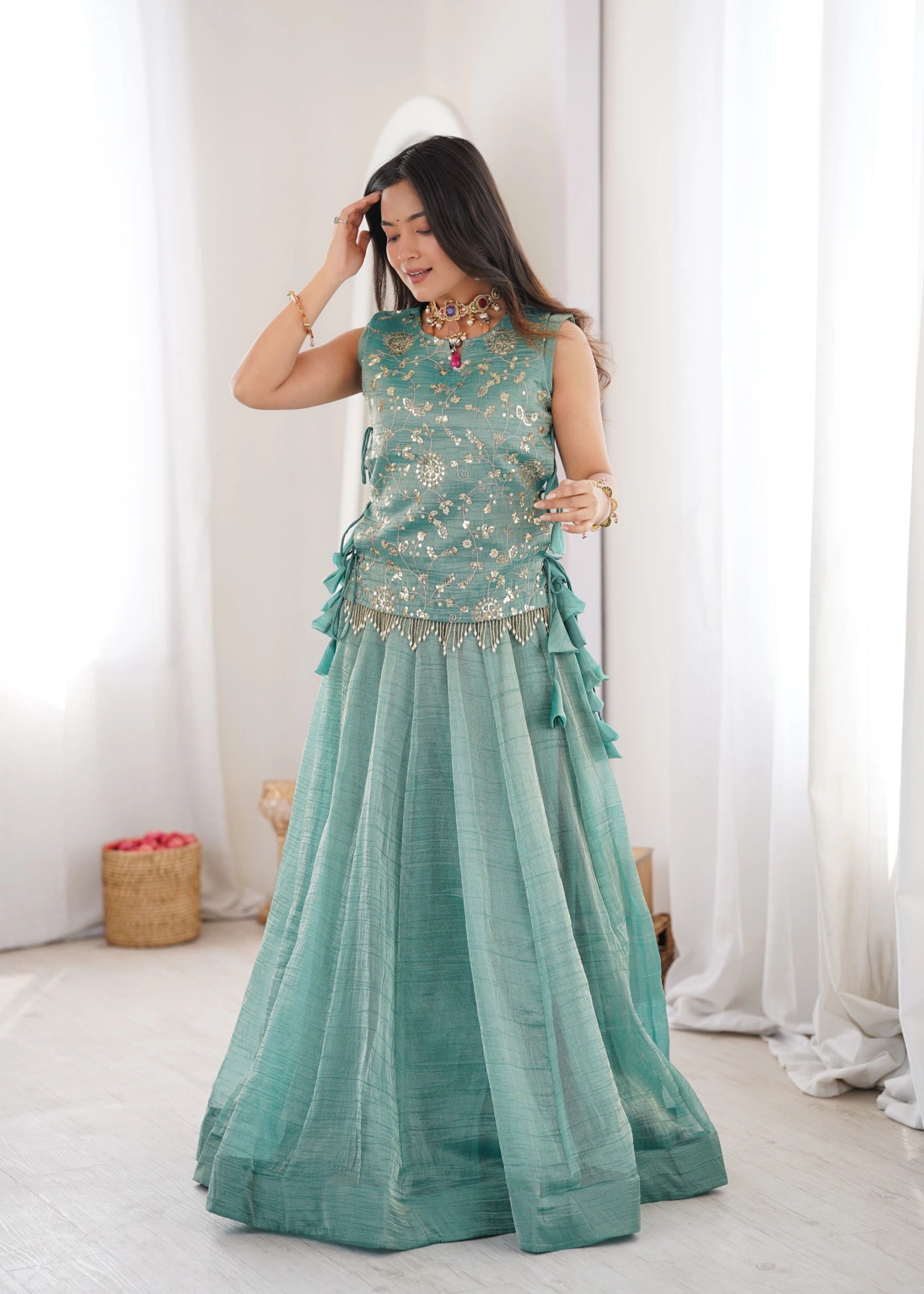 Woman wearing a Sky Blue traditional outfit with white curtains in the background