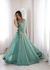 Teal traditional outfit with embroidered top and ruffled dupatta on a stand against a decorative wall.