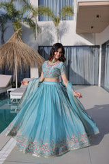 Woman in a blue embroidered traditional outfit by a poolside.