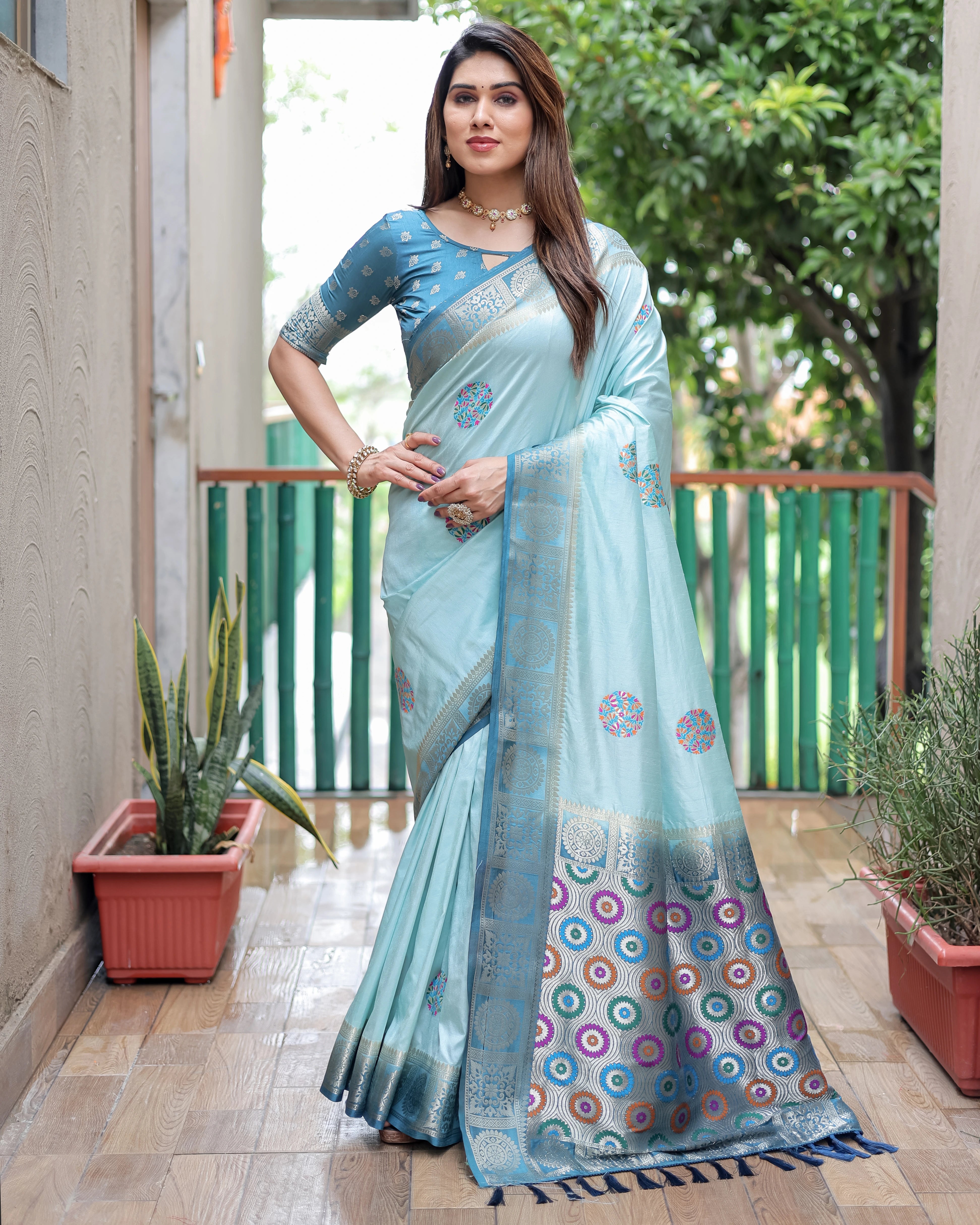 Woman wearing a light blue saree with a patterned border on a balcony.