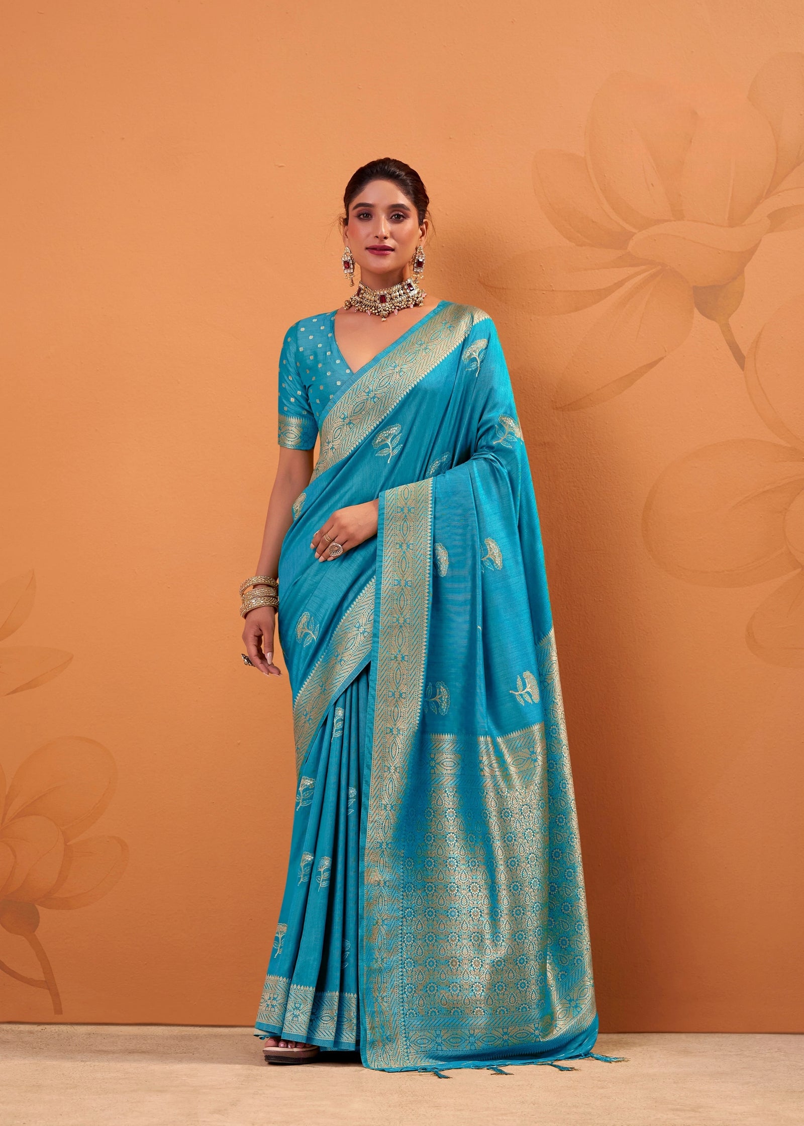 Woman wearing a blue saree with a gold border against an orange background
