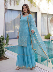 Woman in a light blue traditional outfit standing by a poolside.