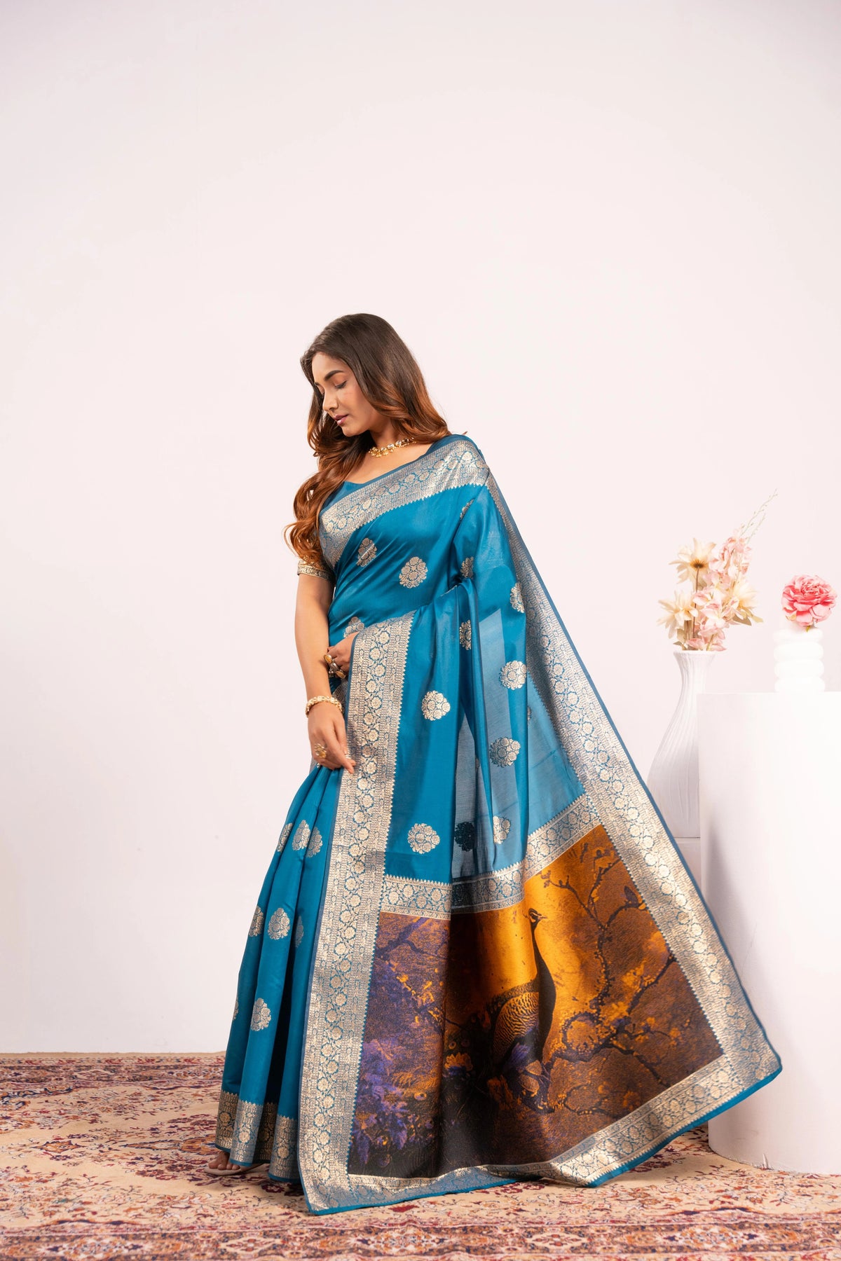 Woman wearing a blue saree with a scenic design on a white background