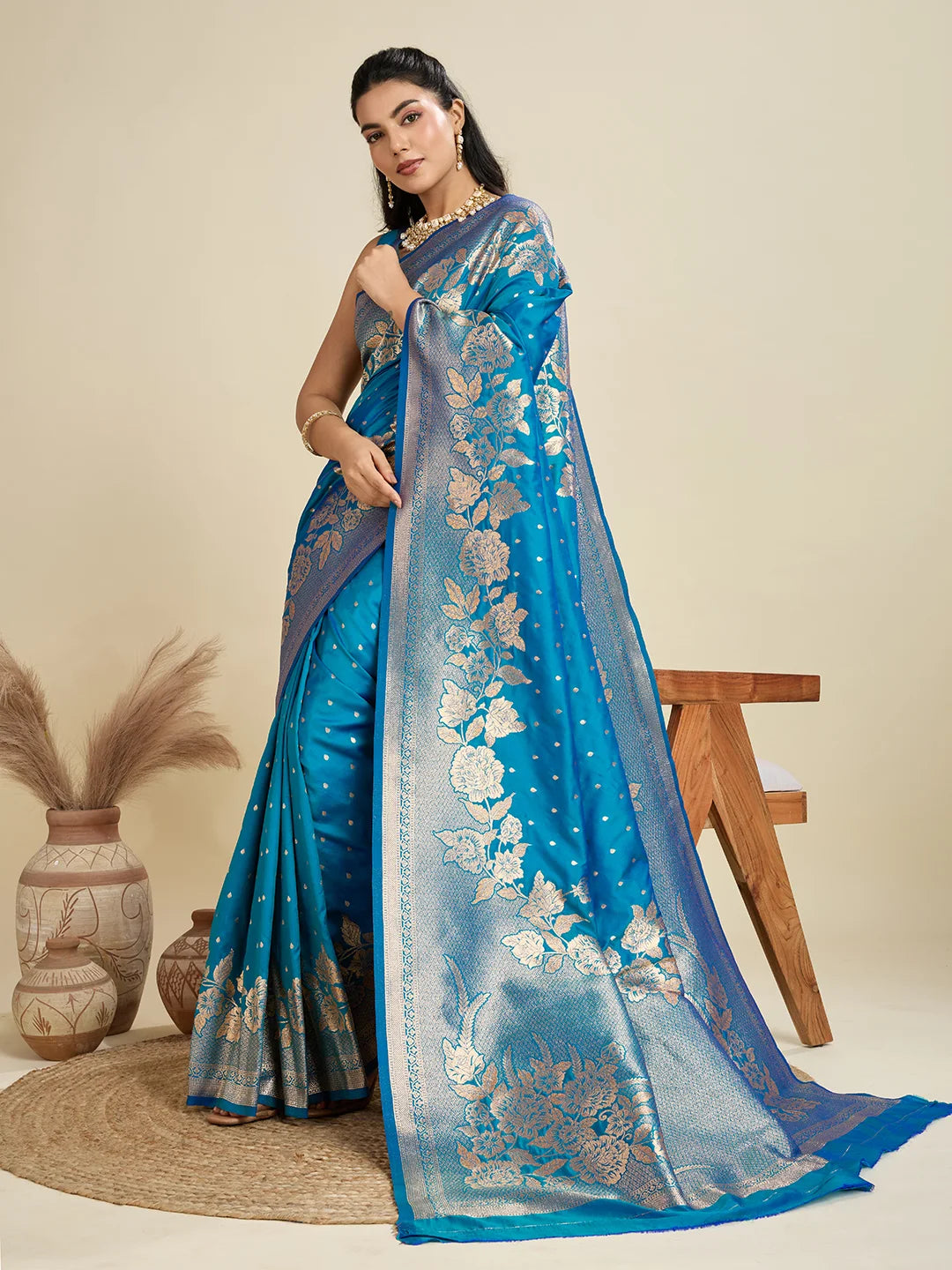 Woman wearing a blue saree with floral patterns on a beige background