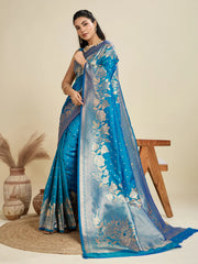 Woman wearing a blue saree with floral patterns on a beige background