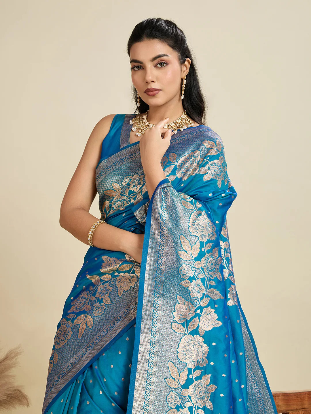 Woman wearing a blue saree with floral patterns on a beige background