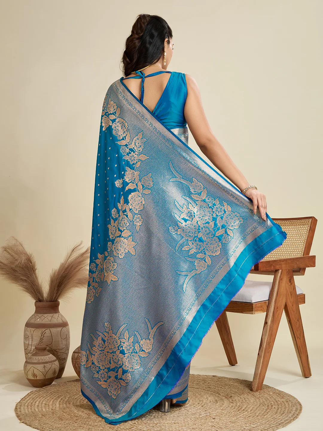 Woman holding a blue saree with floral patterns in a minimalistic setting