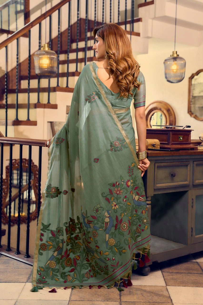 Woman in a light blue saree with floral patterns in an indoor setting