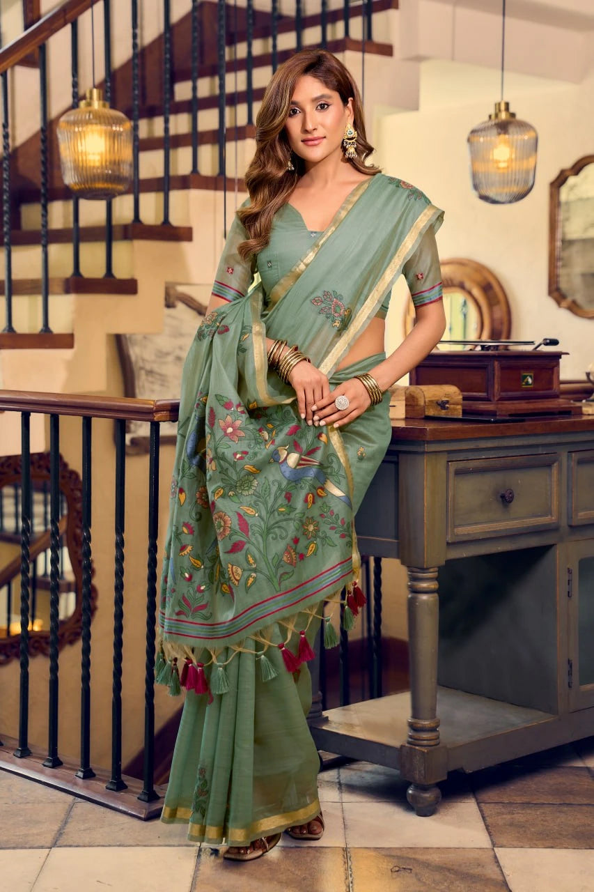 Woman in a green saree with floral patterns in an indoor setting
