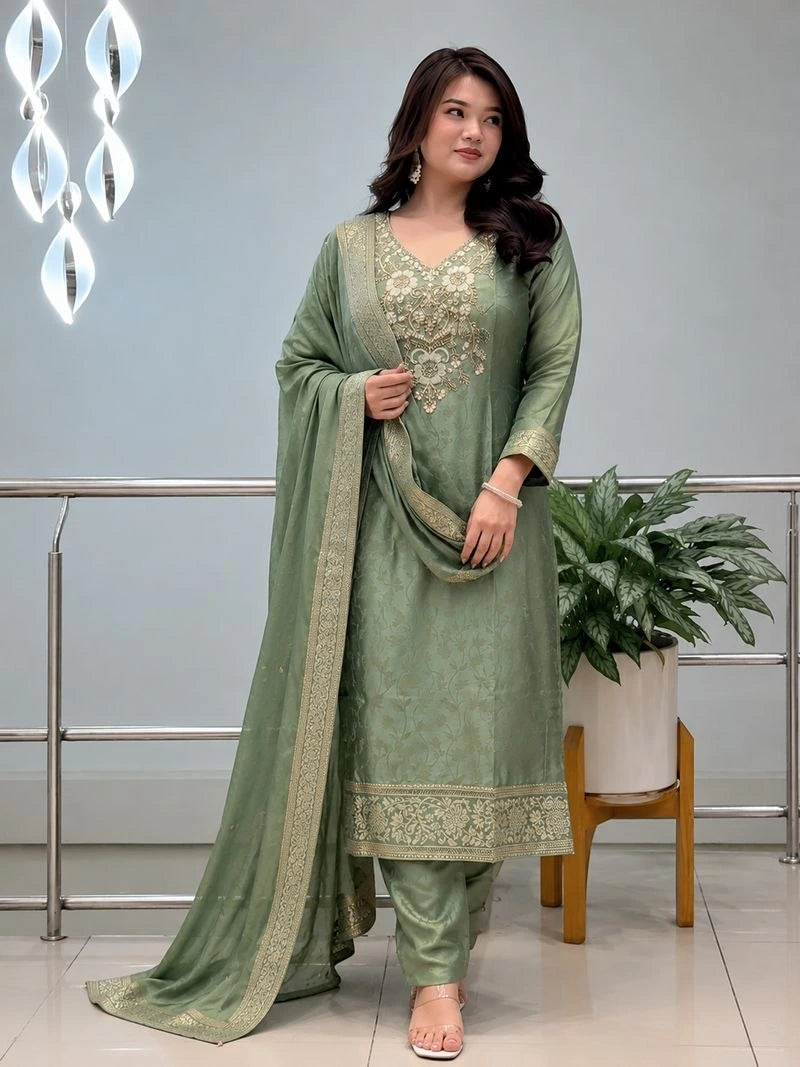 Woman wearing a green traditional outfit with embroidery in an indoor setting.